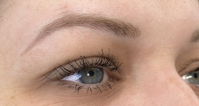 Kvinde ser resultatet af sin permanente makeup i spejlet.