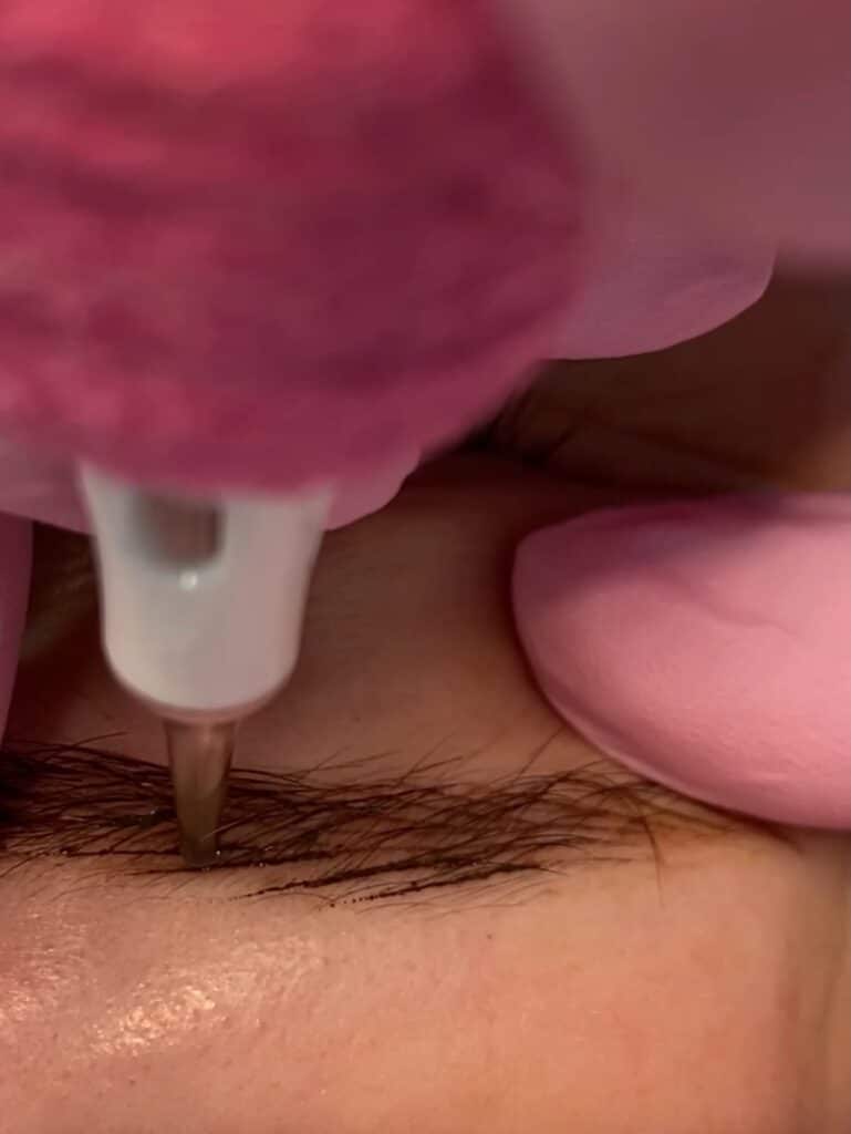 Tæt på tatovering af øjenbryn med maskine – fine hårstrå skabes med præcision