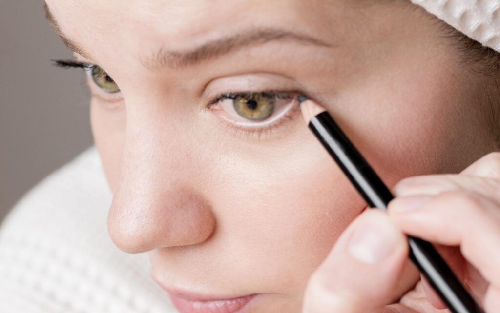 Person får optegnet eyeliner-design hos kosmetisk behandler